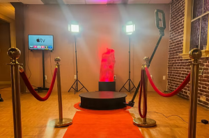 BOMBA Creative Co.'s luxury 360 photo booth setup with premium red carpet experience, professional studio lighting, and branded circular platform. Complete with velvet stanchions, monitor display, and our signature orange/red color scheme. Perfect for high-end events in Orlando and Central Florida. The ultimate VIP photo experience for weddings, corporate events, and luxury social gatherings.