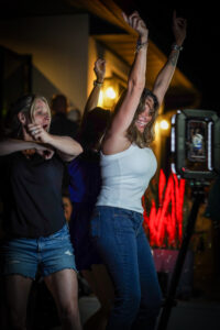 BOMBA Creative Co.'s 360 photo booth creating unforgettable moments at a nightlife event in Orlando with excited guests celebrating with arms raised. The premium photo experience captures genuine joy and energy with our professional equipment visible in the foreground. Perfect for luxury social gatherings, private parties, and nightlife venues in Central Florida.