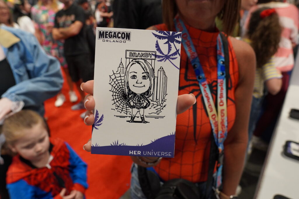 MegaCon Orlando attendee holding a personalized Spider-Man-themed AI Sketch Bot caricature created by BOMBA Creative Co. for Her Universe.